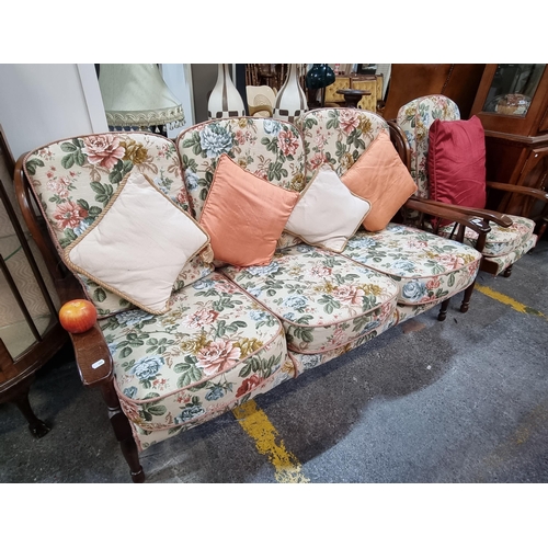 556 - Star Lot : A three seater spindle backed sofa with matching armchair. The floral upholstery is in go... 