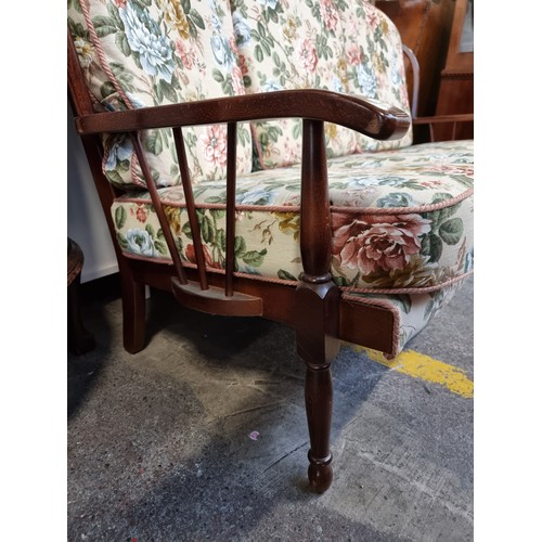 556 - Star Lot : A three seater spindle backed sofa with matching armchair. The floral upholstery is in go... 