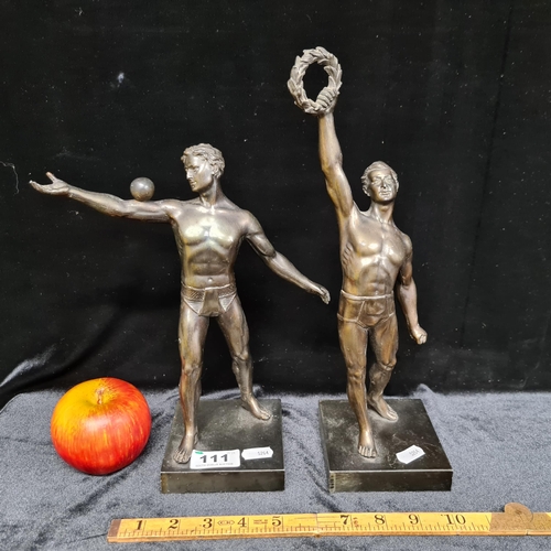 111 - Two heavy, large cast metal Olympic athletes; depicted in a classical style, with one holding a wrea... 