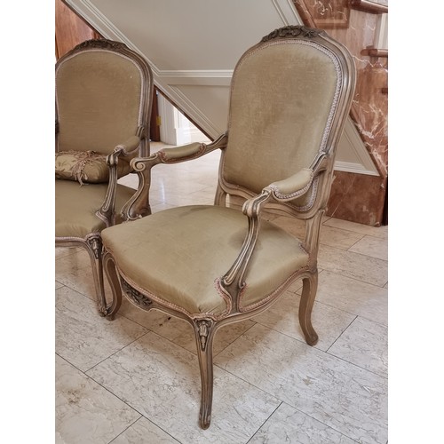 43 - A pair of large French style open armchairs with padded arm rests, scroll relief carving, and cabrio... 