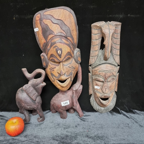 149 - Three traditional hand carved African decorative pieces, including a stylised elephant and two mask ... 