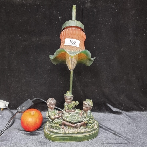 168 - A table lamp with figurative sculptural base featuring three children playing a game of cards, with ... 