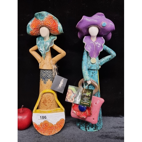 186 - Two bright and colourful figurative clay sculptures of ladies in fashionable outfits with oversized ... 