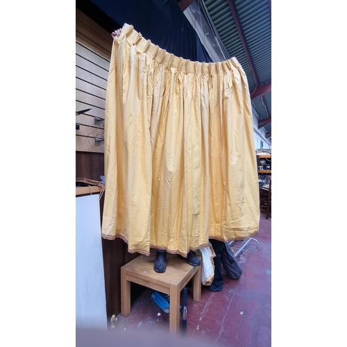 379 - A heavy pair of lined curtains in apricot with red and yellow woven trim and with a pair of matching... 