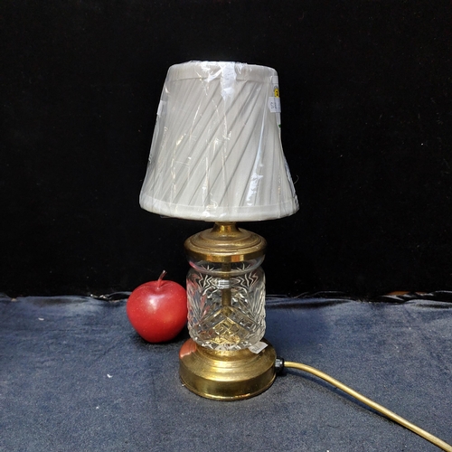 416 - A brass toned desk lamb with a cut crystal body. With a cellophane wrapped ivory shade.