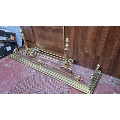 377 - 7 brass fireside items including a fire fender (Interior length 124cm) with a pair of large fire dog... 