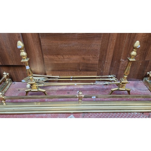 377 - 7 brass fireside items including a fire fender (Interior length 124cm) with a pair of large fire dog... 