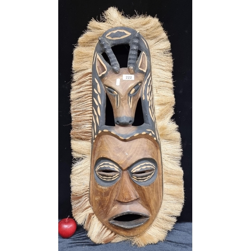 222 - A very large African wood carved mask, with pierced detail depicting a face and antelope encased in ... 