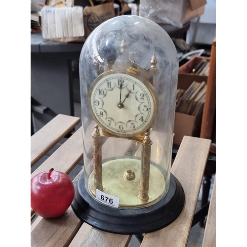 A lovely vintage glass dome mantle clock with intricately carved supports and a garland motif on the