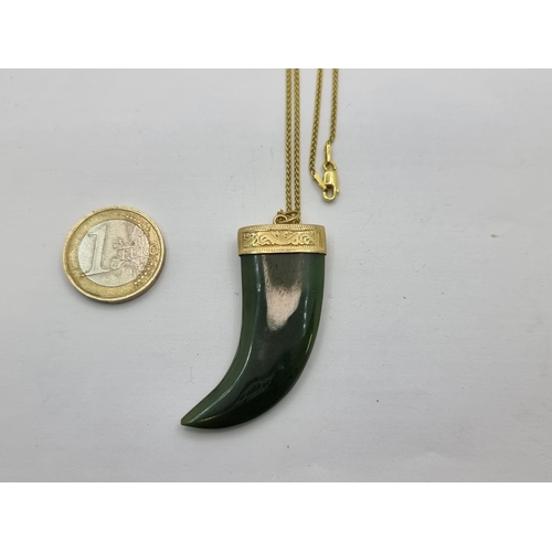 33 - An unmarked 9K gold jade stone pendant, in the form an tiger tooth. Total weight 13.85g. Jade cold t... 