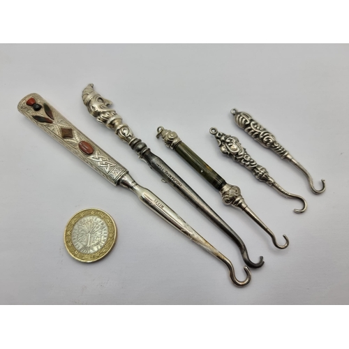 38 - A collection of five antique sterling silver topped items in the style of sewing/boot hooks. One wit... 
