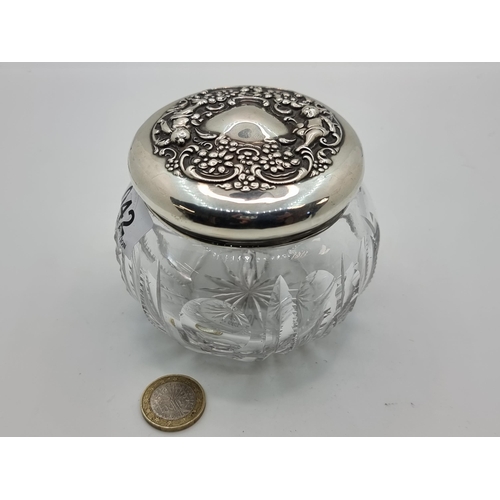 42 - A dressing table jar with sterling silver Rococo designed lid and cut glass base. In super condition... 