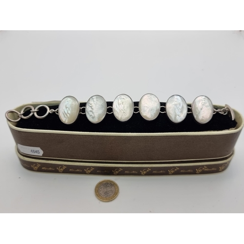 44 - A six stone Sterling Silver mother of pearl bracelet, length 19cm. Contained in Rhinestones of Dubli... 