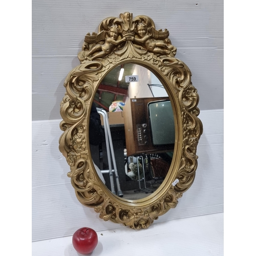 759 - A good sized oval wall hanging mirror with a ornate baroque style gilt frame.