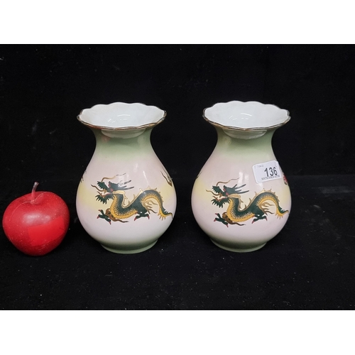 136 - A pair of elegant vintage porcelain vases with Japanese dragon motif and gilt detail on a graduating... 