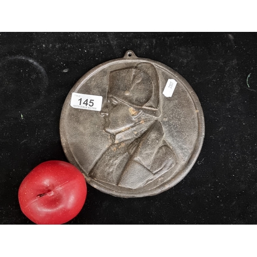 145 - A heavy cast metal circular plaque featuring a cameo of Napoleon in relief.