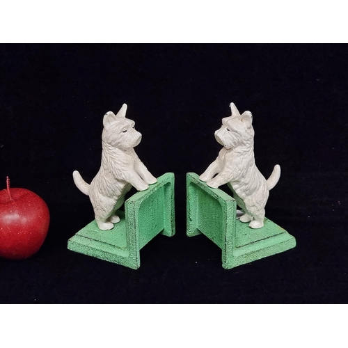 174 - A pair of very heavy cast metal bookends featuring playful West Highland terriers on a mint green ba... 