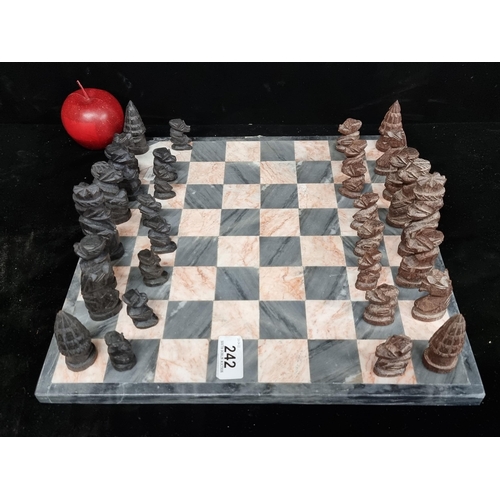 242 - A very heavy marble chess board in tones of grey and blush with hand carved wooden chess pieces. Com... 