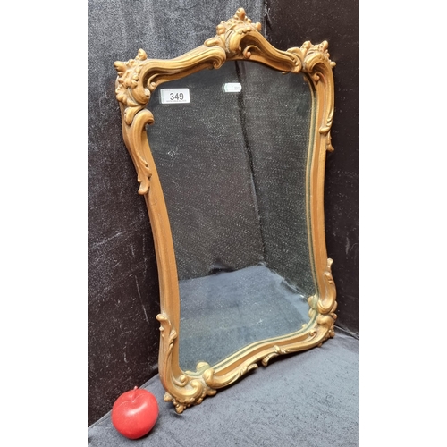 An antique wall hanging mirror with a curve-linear gilt wooden frame.