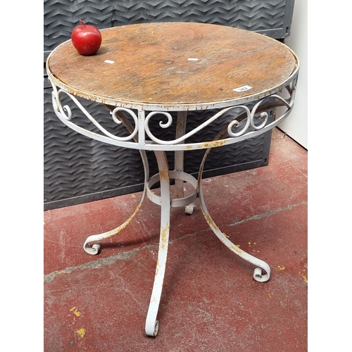 382 - A lovely round wrought iron outdoor table with wooden top, in white.