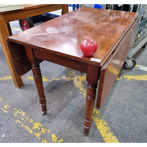 393 - An antique mahogany drop leaf table with turned legs on brass casters. Mm: L90cm x W107cm (fully ext... 