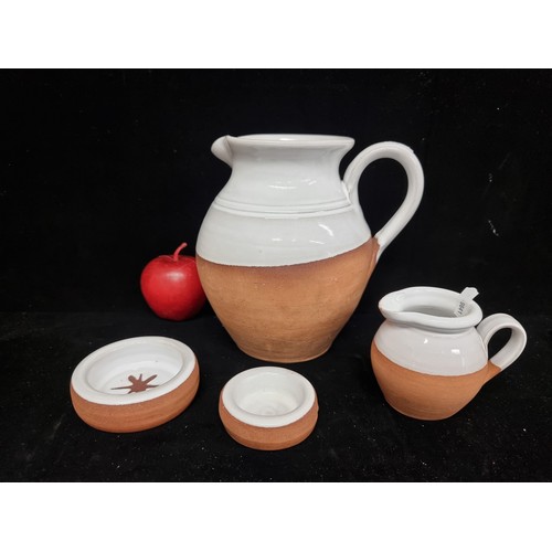 243 - Four pieces of terracotta pottery by Stephen Pearce including a water jug, milk jug and ramekins. SD