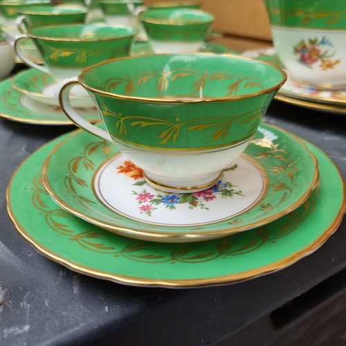 387 - Thirty nine pieces of china tableware with a bright green and gilt border decorated with a floral mo... 