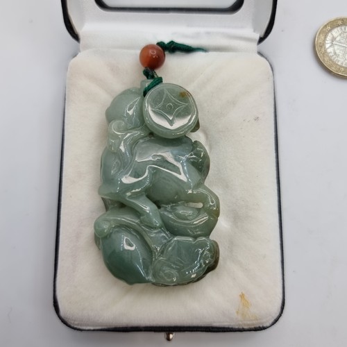 343 - A beautiful green jade hand carved pendant in the form of a water buffalo traversing through foliage... 