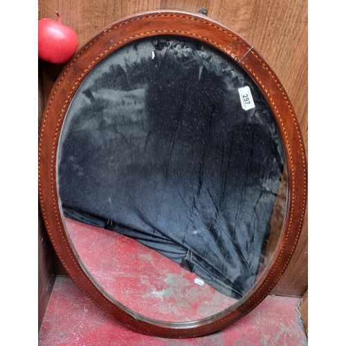 297 - A large Edwardian oval mirror, with a string inlay border throughout the mahogany frame. L82cm x H58... 