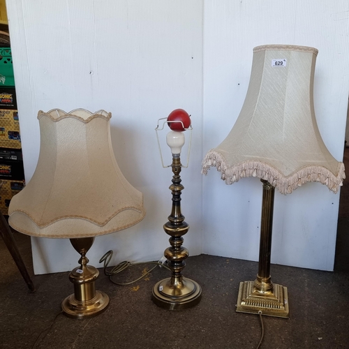629 - Three very tall brass toned table lamps including one Corinthian column example and two with cream l... 