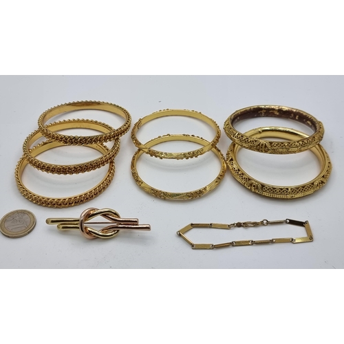 648 - A good collection of seven gold toned bangles, each with intricate design. Together with a two toned... 