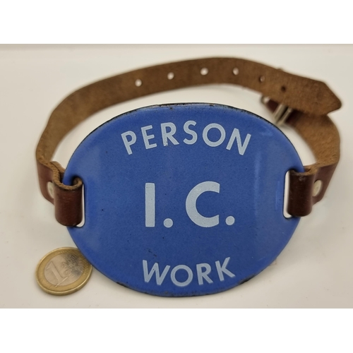 650 - An enamelled arm band with leather strap tie, stating 