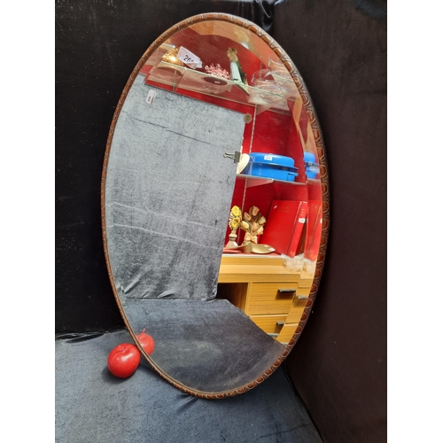 269 - A lovely oval antique bevelled mirror with a slim carved wooden frame. Mm: 73cm x 49cm.