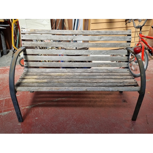 298 - A lovely outdoor bench with metal frame and wooden slatted seat.  Nice covered arm construction.