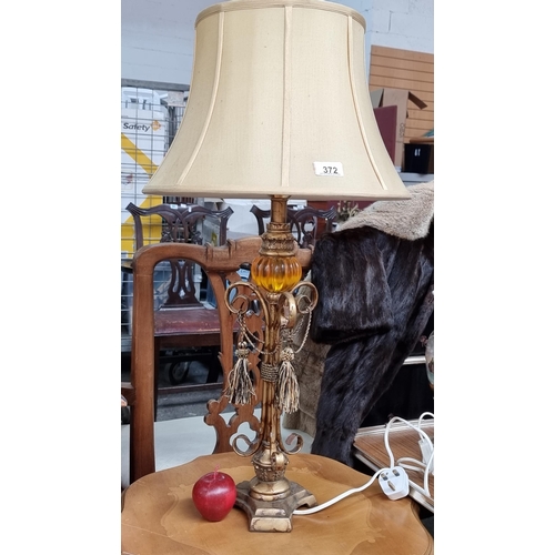 372 - A very attractive table lamp, featuring a gadrooned amber sphere atop an elaborately scrolled stem a... 