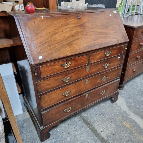 A large Georgian mahogany writing bureau with 5 drawers with brass drop handles and a drop down writing surface with ample storage inside. With a Mealys auctiuon country house sticker. Approx 200 years old.