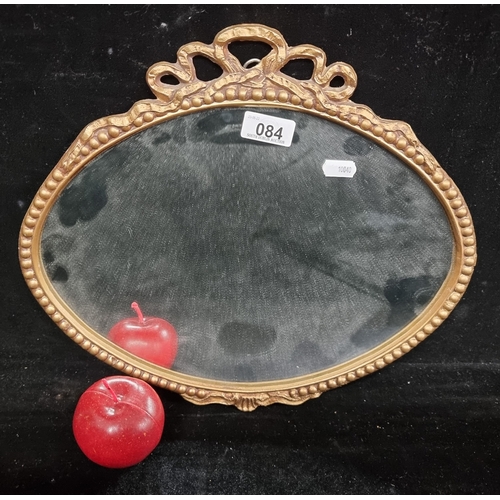 84 - A lovely oval wall mirror with a lavishly gilded frame surmounted with ribbon detail.