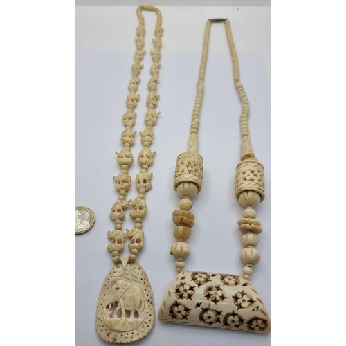 429 - Two extremely attractive Victorian Ivory pendant necklaces. The first example showcases intricate cu... 