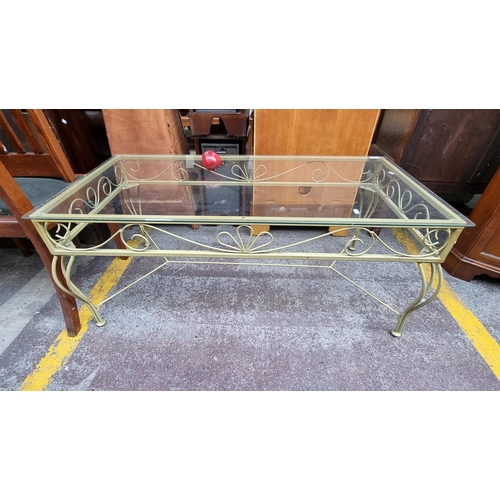 497 - A large rectangular glass topped coffee table with a gold toned, wrought iron base.