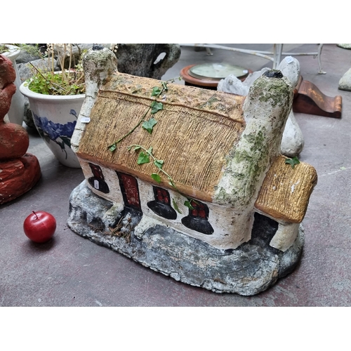 674 - A very very heavy garden statue in the form of a traditional thatched Irish cottage with hand painte... 