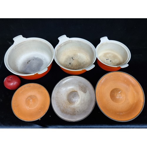 238 - A set of three Le Creuset cast iron graduating lidded dishes, finished in the brands iconic shade of... 