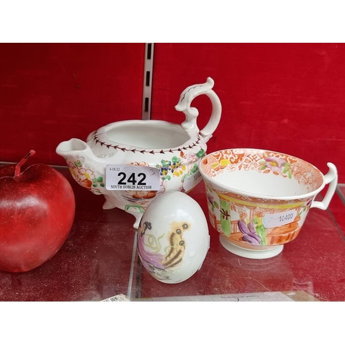 242 - A selection on three ceramic items including a fine teacup, an elaborate footed milk jug and an egg,... 