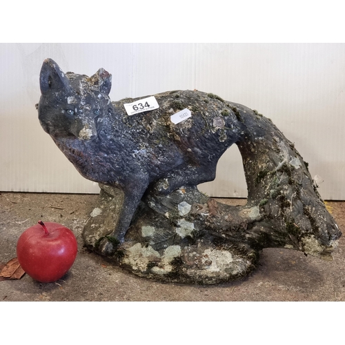 634 - A very heavy reconstituted stone garden ornament of a wiley fox perched on a log.