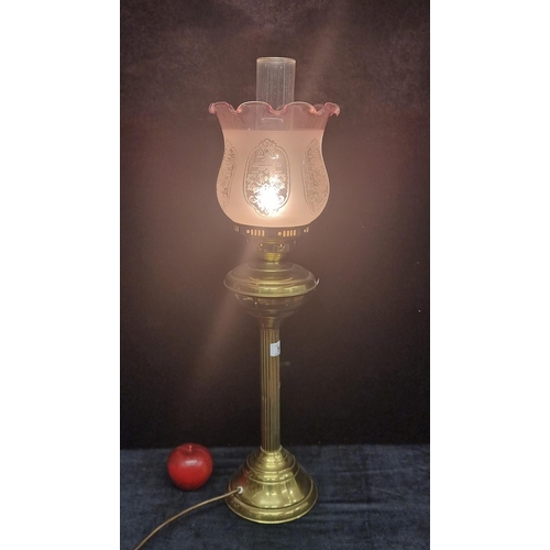 146 - An elegant oil lamp with reeded brass stem, glass chimney and a delicate fluted pink shade with fros... 