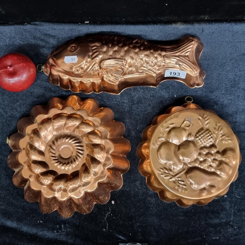 193 - Three vintage copper jelly moulds one in the form of a fish, the other two showing flowers and fruit... 