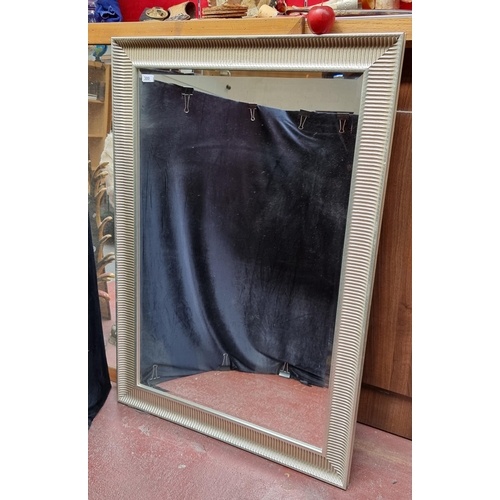 300 - A very large wall hanging bevelled mirror with contemporary silver toned frame.