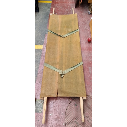 303 - A WW2 field stretcher with wooden frame and retractable handles. With canvas base.