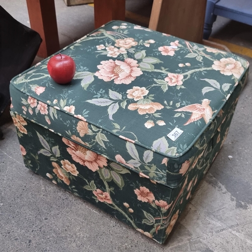 367 - A cushioned ottoman with storage capacity and hinged lid, upholstered in a floral fabric.