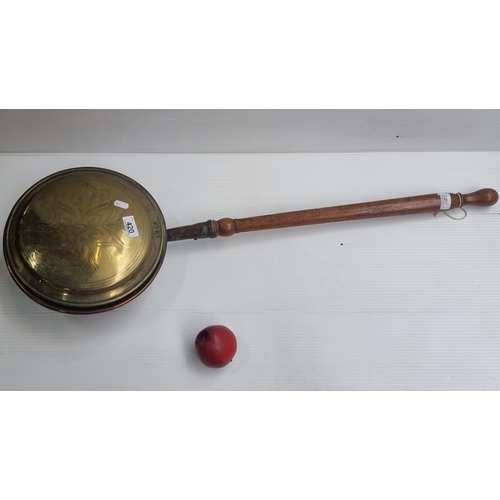 420 - A large antique brass bed warmer with oak handle and incised ornament to top.