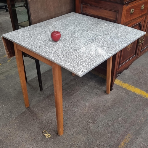 425 - A mid century drop leaf table with stone effect Formica top, metal edging and teak wooden legs.